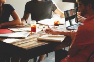 People meeting around a table with laptops, notebooks, iced tea, and iced coffee